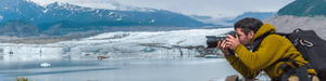 Man in yellow sweater taking photos in an icy landscape