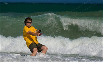 Man standing in the surf flying a power kite