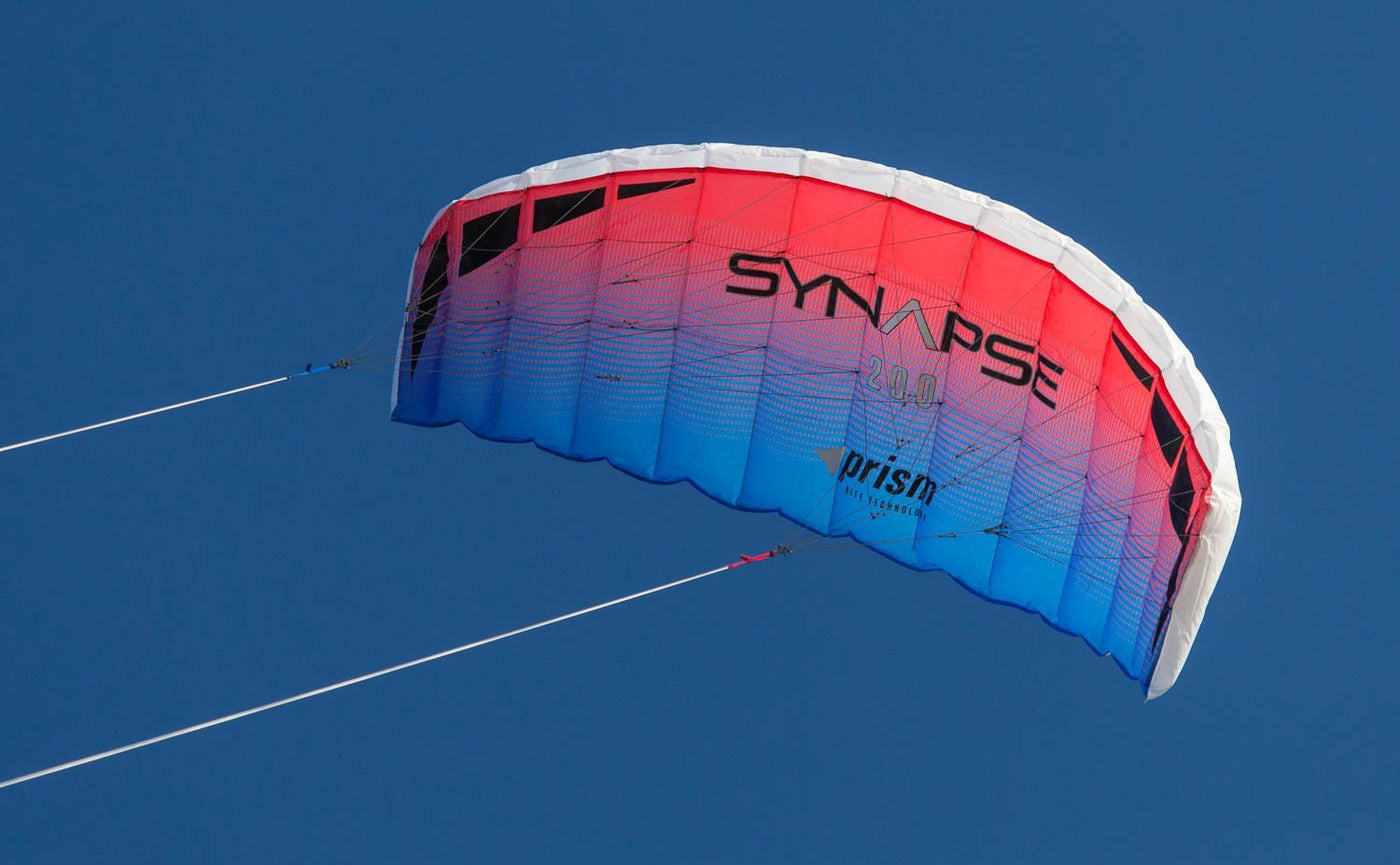 A red and blue Synapse 200 dual-line parafoil against a cloudless sky